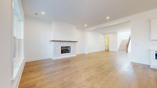 unfurnished living room featuring a premium fireplace and light wood-type flooring