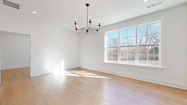 unfurnished room featuring an inviting chandelier and light hardwood / wood-style floors