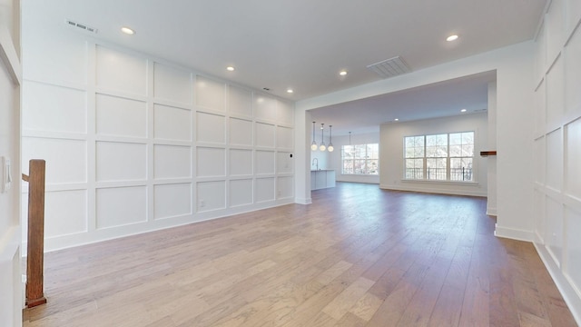 unfurnished living room featuring a chandelier and light hardwood / wood-style flooring