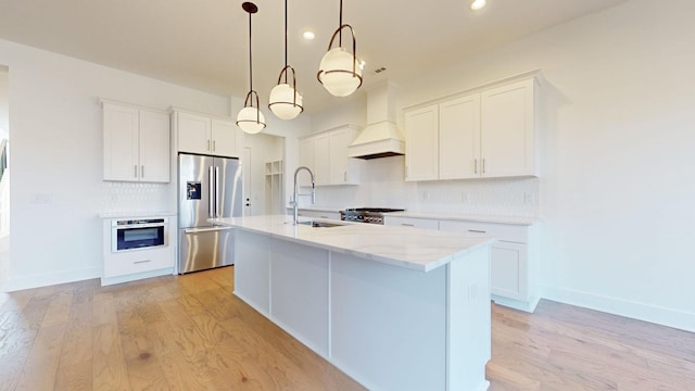 kitchen featuring sink, appliances with stainless steel finishes, white cabinetry, hanging light fixtures, and custom range hood