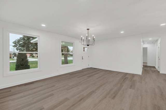 unfurnished dining area featuring an inviting chandelier and light hardwood / wood-style floors