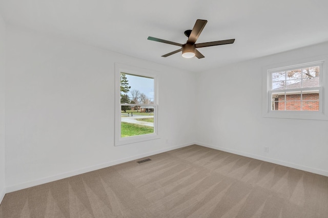 carpeted spare room with plenty of natural light and ceiling fan