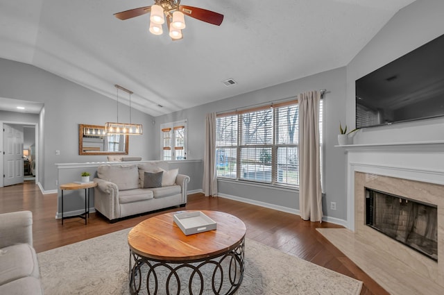 living room with lofted ceiling, a fireplace, wood finished floors, visible vents, and baseboards