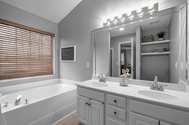 full bath featuring tile patterned floors, double vanity, a sink, and a bath