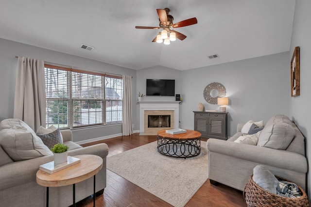 living room with lofted ceiling, visible vents, dark wood finished floors, and a tile fireplace