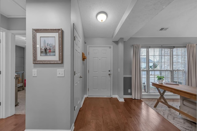 entrance foyer with visible vents, a textured ceiling, baseboards, and wood finished floors