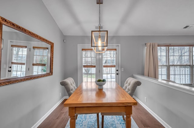 dining area featuring dark wood-style floors, vaulted ceiling, a wealth of natural light, and baseboards