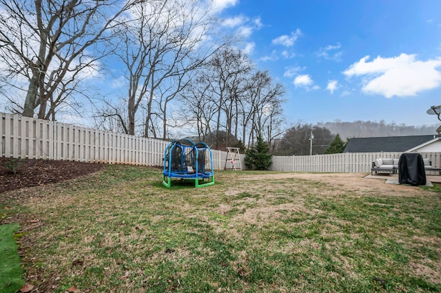 view of yard with a trampoline and a fenced backyard