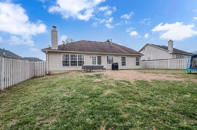 rear view of house with a lawn, a trampoline, a fenced backyard, and a jacuzzi