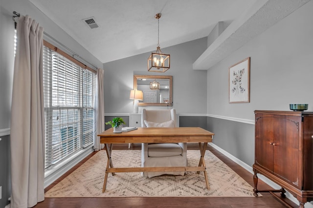 home office featuring lofted ceiling, wood finished floors, visible vents, and a notable chandelier