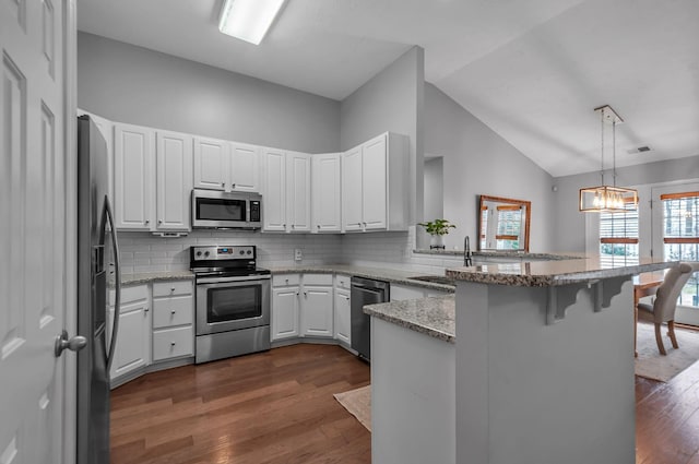 kitchen featuring pendant lighting, appliances with stainless steel finishes, white cabinetry, a peninsula, and a kitchen breakfast bar