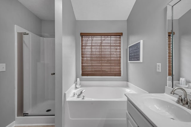 bathroom with a garden tub, a shower stall, a textured ceiling, and vanity