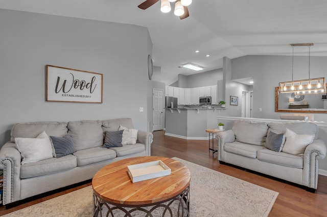 living area with a ceiling fan, high vaulted ceiling, baseboards, and wood finished floors