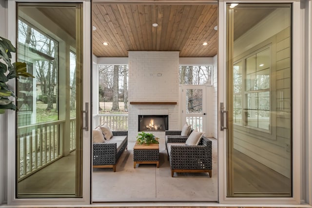 sunroom featuring an outdoor brick fireplace and wood ceiling