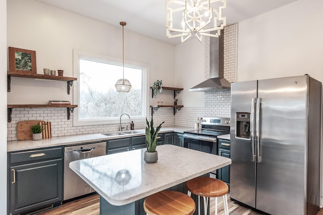 kitchen featuring appliances with stainless steel finishes, pendant lighting, sink, a kitchen breakfast bar, and wall chimney range hood