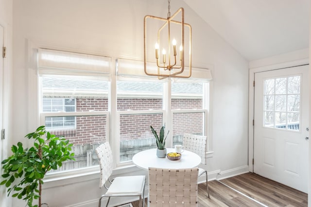 dining area featuring an inviting chandelier, wood-type flooring, and vaulted ceiling