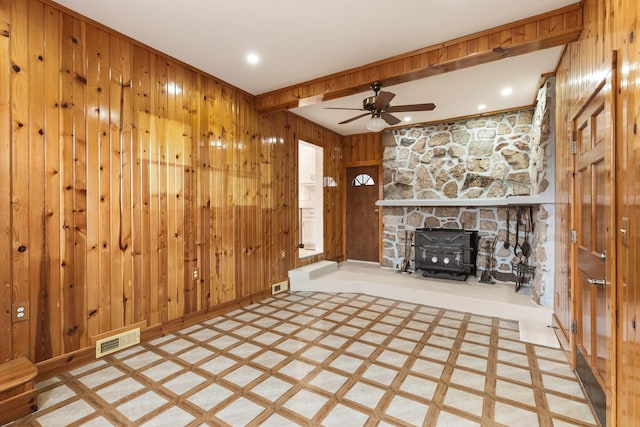 unfurnished living room featuring beamed ceiling, ceiling fan, and wood walls