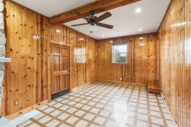 unfurnished room featuring ceiling fan and wood walls