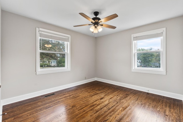 unfurnished room with ceiling fan, dark wood-type flooring, and a healthy amount of sunlight