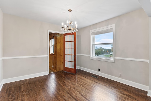 empty room with dark wood-type flooring and a chandelier