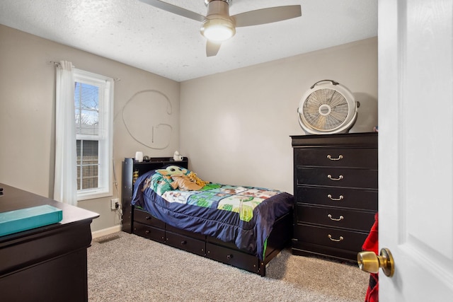 bedroom featuring a textured ceiling, light colored carpet, and ceiling fan