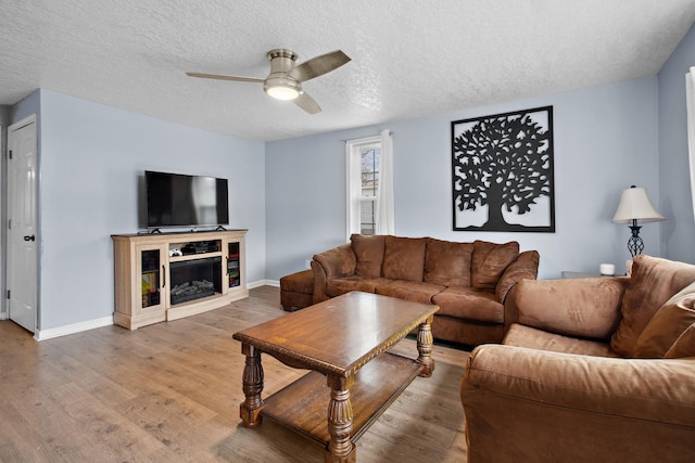 living room with hardwood / wood-style flooring, ceiling fan, and a textured ceiling