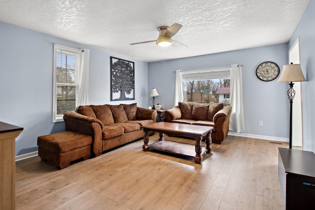 living room featuring ceiling fan, a healthy amount of sunlight, light hardwood / wood-style floors, and a textured ceiling