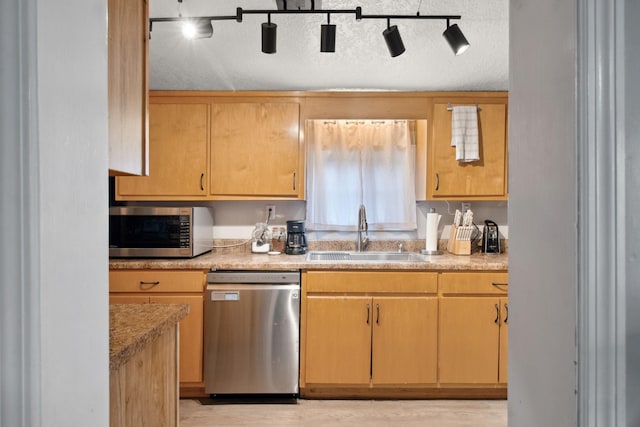 kitchen featuring stainless steel appliances, sink, light brown cabinetry, and a textured ceiling