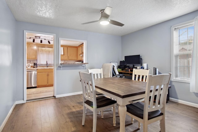 dining area with wood-type flooring, sink, ceiling fan, and a textured ceiling