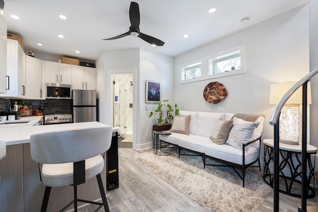 interior space with ceiling fan, sink, and light wood-type flooring