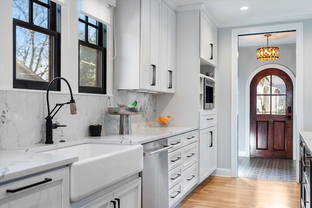 kitchen with white cabinetry, sink, stainless steel dishwasher, and light stone counters