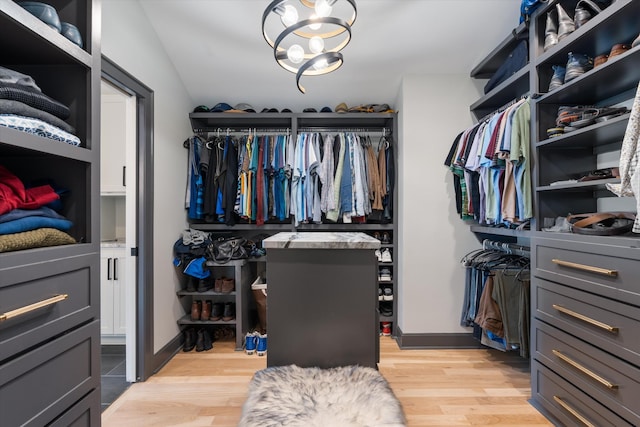 walk in closet with a notable chandelier and light hardwood / wood-style flooring