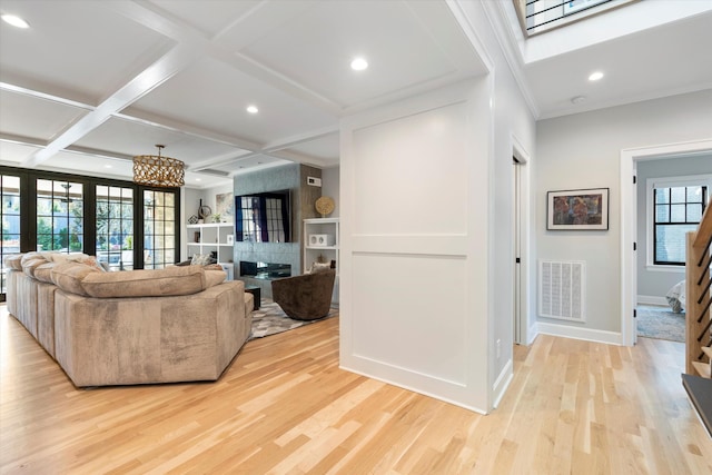 living room featuring coffered ceiling, light hardwood / wood-style floors, and a skylight