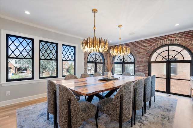 dining area featuring ornamental molding, brick wall, an inviting chandelier, and light wood-type flooring