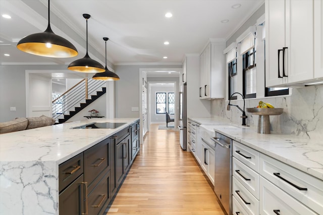 kitchen featuring light stone counters, hanging light fixtures, appliances with stainless steel finishes, ornamental molding, and white cabinets