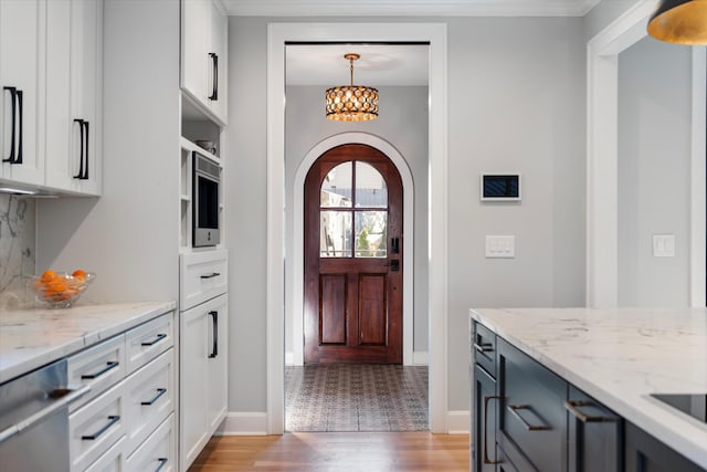 kitchen with crown molding, stainless steel dishwasher, a notable chandelier, and light hardwood / wood-style floors