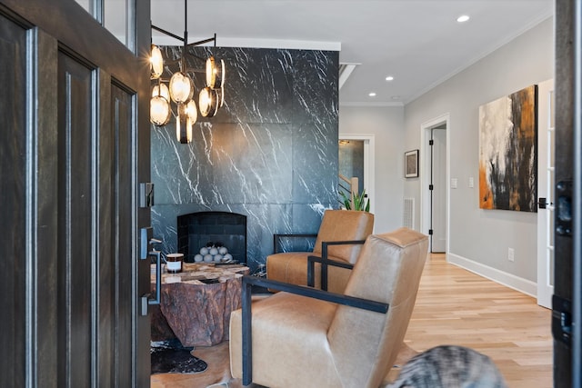 interior space with a notable chandelier, crown molding, a high end fireplace, and hardwood / wood-style flooring