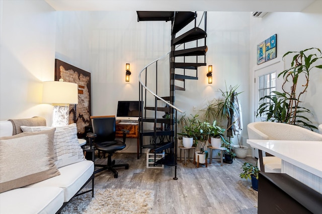 office featuring a towering ceiling and wood-type flooring