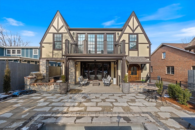 rear view of house with a patio, a balcony, and area for grilling