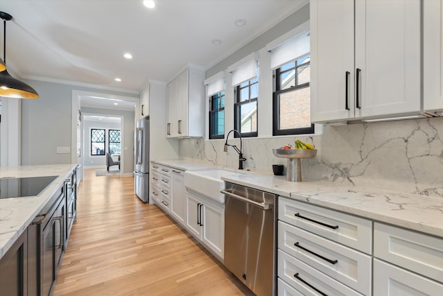 kitchen featuring stainless steel appliances, decorative light fixtures, sink, and white cabinets