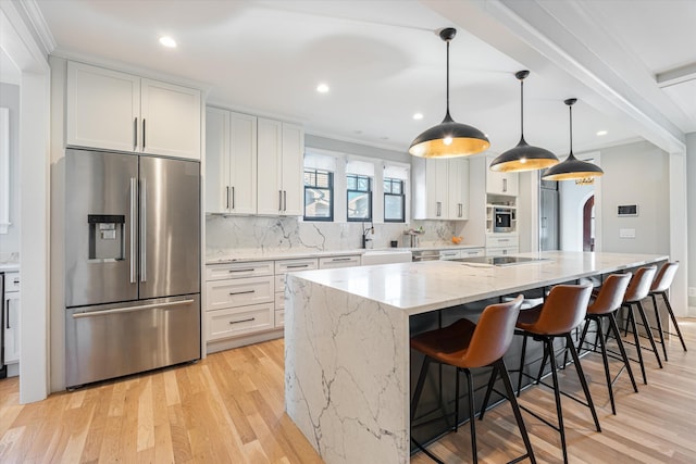 kitchen featuring stainless steel appliances, white cabinetry, hanging light fixtures, and a spacious island