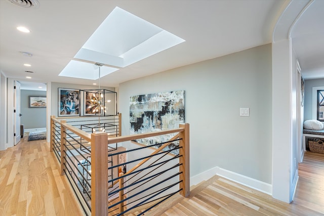 hall featuring a chandelier, a skylight, and hardwood / wood-style floors