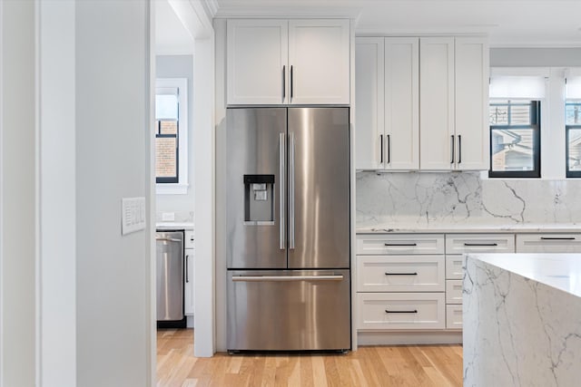 kitchen featuring white cabinetry, stainless steel appliances, light hardwood / wood-style floors, and light stone counters