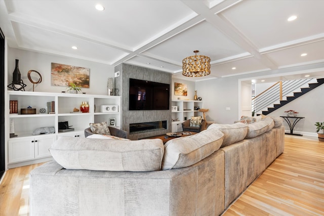 living room with coffered ceiling, a fireplace, and light hardwood / wood-style flooring