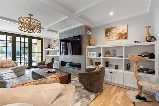 living room featuring a fireplace, beamed ceiling, light hardwood / wood-style flooring, coffered ceiling, and french doors