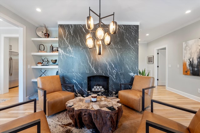 sitting room with crown molding, a high end fireplace, a chandelier, and hardwood / wood-style flooring