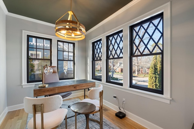 office area featuring ornamental molding, a healthy amount of sunlight, a notable chandelier, and light wood-type flooring