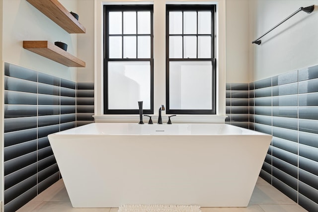 bathroom with tile patterned flooring, a tub, and tile walls