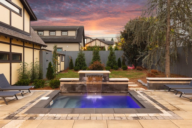 pool at dusk featuring a hot tub and a patio