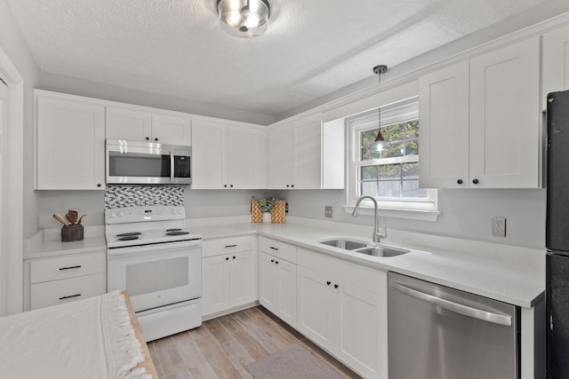 kitchen featuring white cabinetry, appliances with stainless steel finishes, sink, and decorative light fixtures